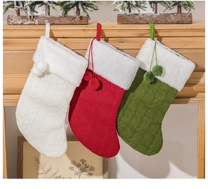 Knitted Christmas stockings with white faux fur cuffs and pom-poms on fireplace