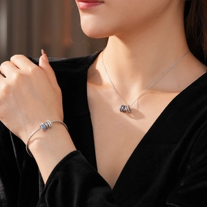 Silver necklace and bracelet set with blue enamel zircon charms worn by a model