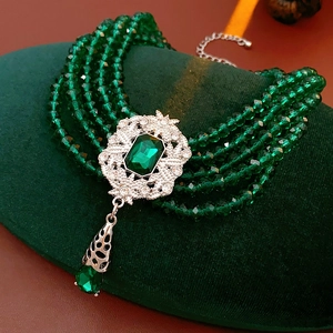 Detail of vintage emerald beaded necklace with ornate silver pendant and drop jewel
