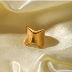 Close-up of golden irregular concave surface ring on beige silk background