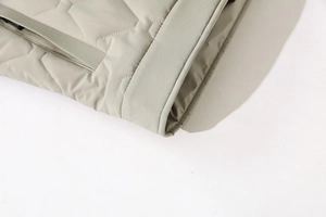 Detail of light beige quilted winter jacket showing ribbed cuffs and windproof stitching