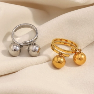 Close-up of gold and silver double ball dangle rings on a white silk fabric surface