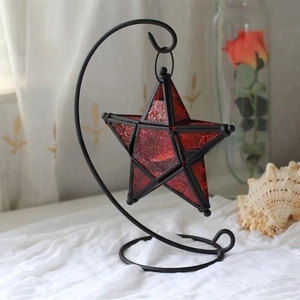 Close-up of Moroccan star candle holder with red embossed glass and black metal stand