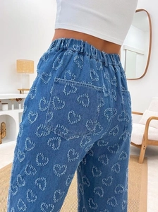 Detailed view of heart-shaped brushed embroidery on blue denim jeans back pockets