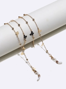 Detail of golden eyeglass chain featuring black butterfly charms and white rubber grips