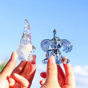 Handmade iridescent glass gnome and elephant crystal figurines set against a blue sky