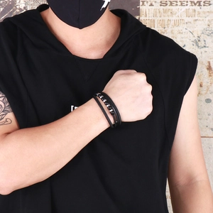 Close-up of men's multi-layer black braided leather bracelet with beads on wrist