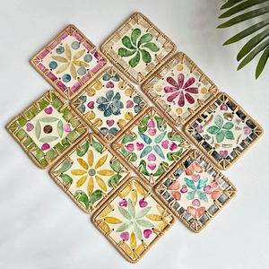 Detailed top view of square rattan coasters with colorful shell floral inlay patterns