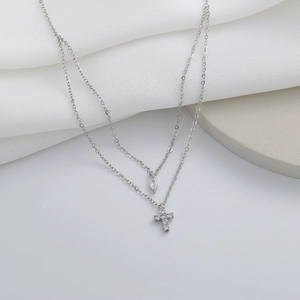 Detail shot of silver double-layered necklace featuring a cross pendant and zircon stone