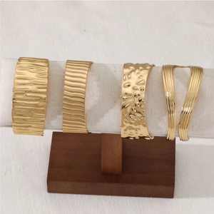 Golden stainless steel wide open bangles with hammered and wave textures on display