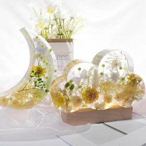 Luminous moon and cloud resin craft with dried flowers on a warm wooden LED base