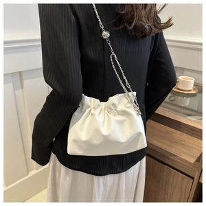 White ruched cloud bucket bag with silver chain strap shown on model's shoulder