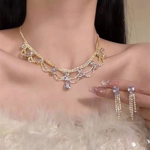 Elegant gold drop earring and necklace set with sparkling crystals worn by a model