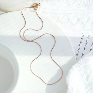 Detail of rose gold snake bone chain with lobster clasp and extension on white surface