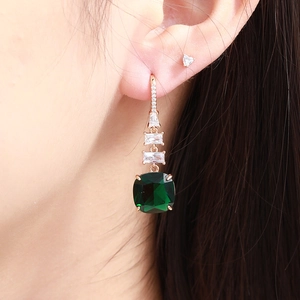 Elegant emerald green teardrop drop earrings with rose gold plating on female model