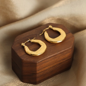 Minimalist gold-plated U-shaped geometric earrings on a luxury jewelry display box