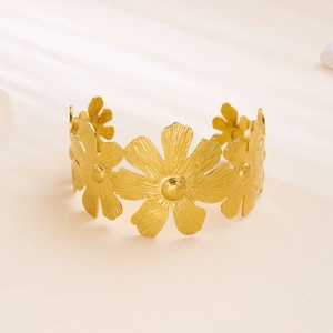 Detail view of gold floral open cuff bracelet with textured daisy petal finish