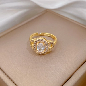 Detailed view of an oval halo ring with sparkling pavé diamonds on a champagne silk background