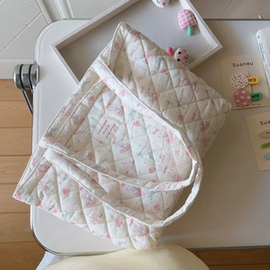 Detail einer gesteppten Baumwolltasche mit weichen rosa Blumen und Schleifenmustern