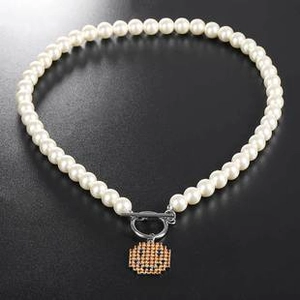 Detail of white pearl necklace with golden smiley pendant and silver OT toggle clasp