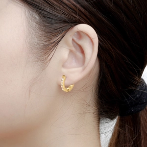 Detailed close-up of 18K gold-plated earring with sparkling crystals on a female model