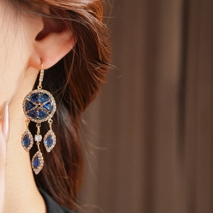 Close-up of vintage gold tassel earrings with navy blue stones and rhinestones on a model
