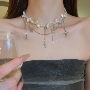 Gros plan d'un collier en perles baroques avec pendentif étoile porté par un modèle