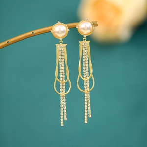 Macro shot of long tassel pearl earrings with golden metal chains and sparkling crystals