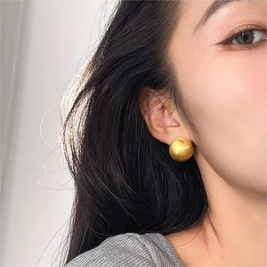 Minimalist matte gold semi-sphere stud earrings for women shown on a model