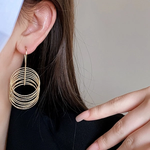 Detail of gold multi-layered hoop earrings worn by a model to show size and drape