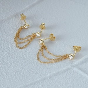 Close-up of 925 sterling silver hallmark on gold chain earrings with sparkling stones