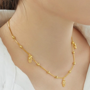 Golden S925 sterling silver beaded necklace with Hamsa Hand pendants worn by a model