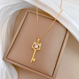 Detailed close-up of a golden cat-shaped key pendant with zircon on a white silk background