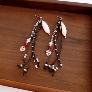 Long tassel earrings featuring silver chains, white pendants and engraved love heart charm
