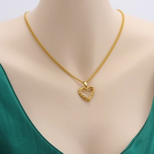 Detailed view of golden heart pendant with hammered texture on a model neck