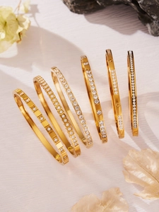 Dettaglio del set di bracciali dorati di lusso con zirconi brillanti e incisioni a stella