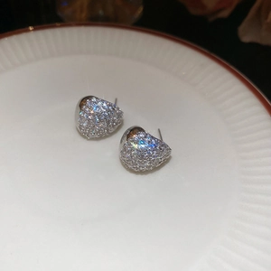 Macro shot of silver drop stud earrings with pave-set zircons on a white porcelain dish