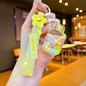 Close-up of Sakura-themed liquid sand keychain with yellow ribbon and pastel spheres