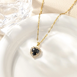 Macro shot of heart-shaped black stone pendant with pavé cubic zirconia on gold chain