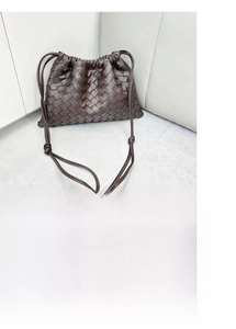 Detail of dark brown woven leather shoulder bag with drawstring and knotted strap design