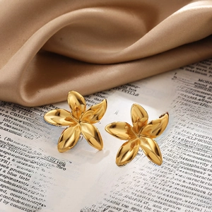 Detailed close-up of 18k gold-plated sunflower pearl earrings on a soft silk fabric base