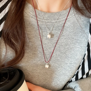 Detail of layered silver chain and burgundy cord necklace with polished ball pendants