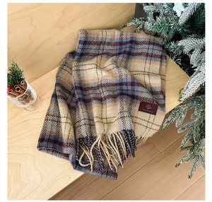 Close-up of a red and beige checkered scarf with fringe on a warm wooden table