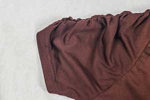 Detailed close-up of dark brown ruched sleeve design with precise stitching on dress