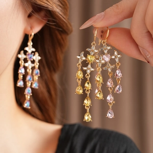 Detail of vintage gold earrings with colorful crystals and tassels on brown background
