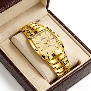 Detail van goudkleurig tonneau horloge met kristallen indexen en dag-datum weergave