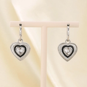 Detail of silver heart earrings with black enamel and heart-shaped zircon on satin