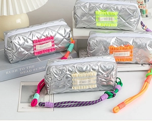 Detail of quilted metallic pencil cases with ruffled patches and woven rope zippers