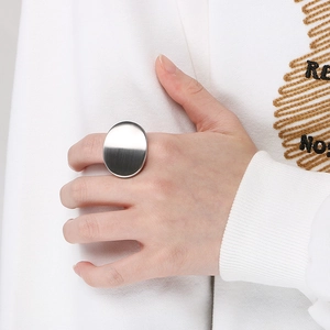 Detailed close-up of a large oval brushed stainless steel ring on a finger