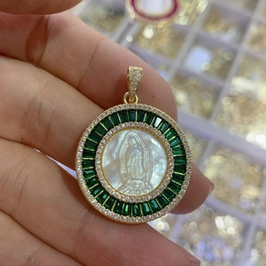 Macro detail of gold Virgin Mary shell pendant with green rectangle and white round stones